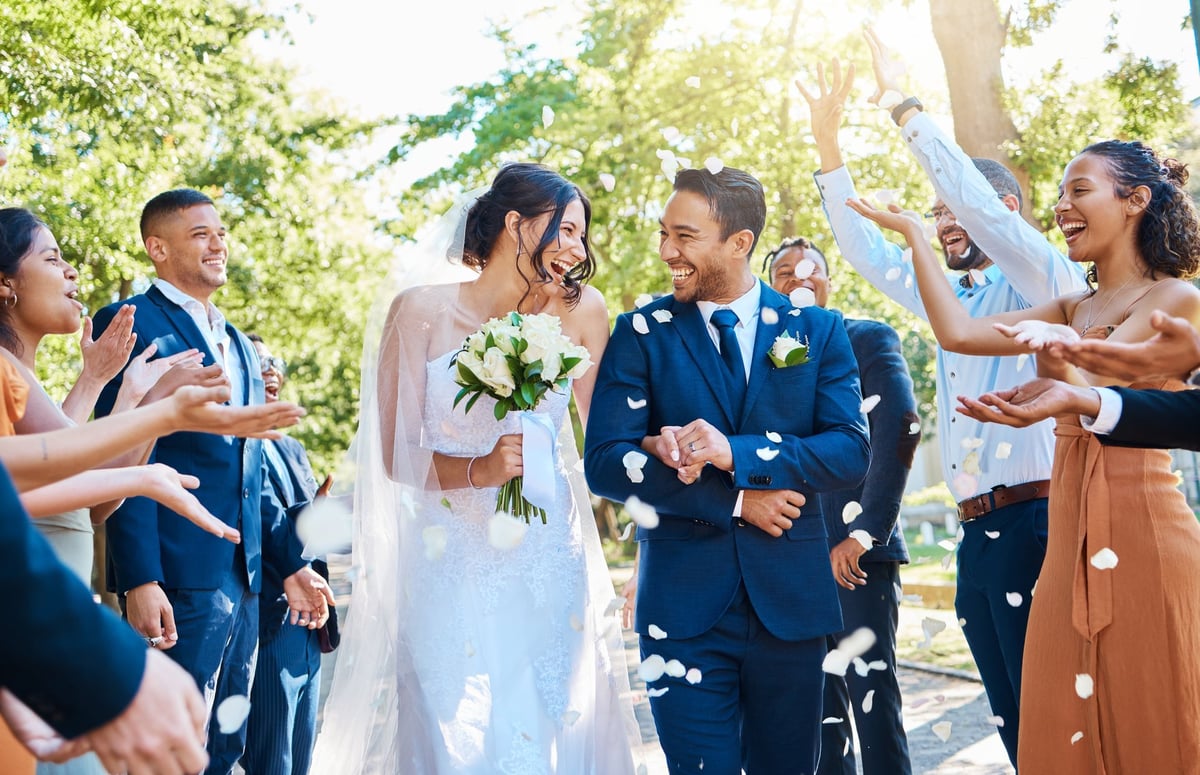 Wedding guests celebrating with rose petals as the couple walks through
