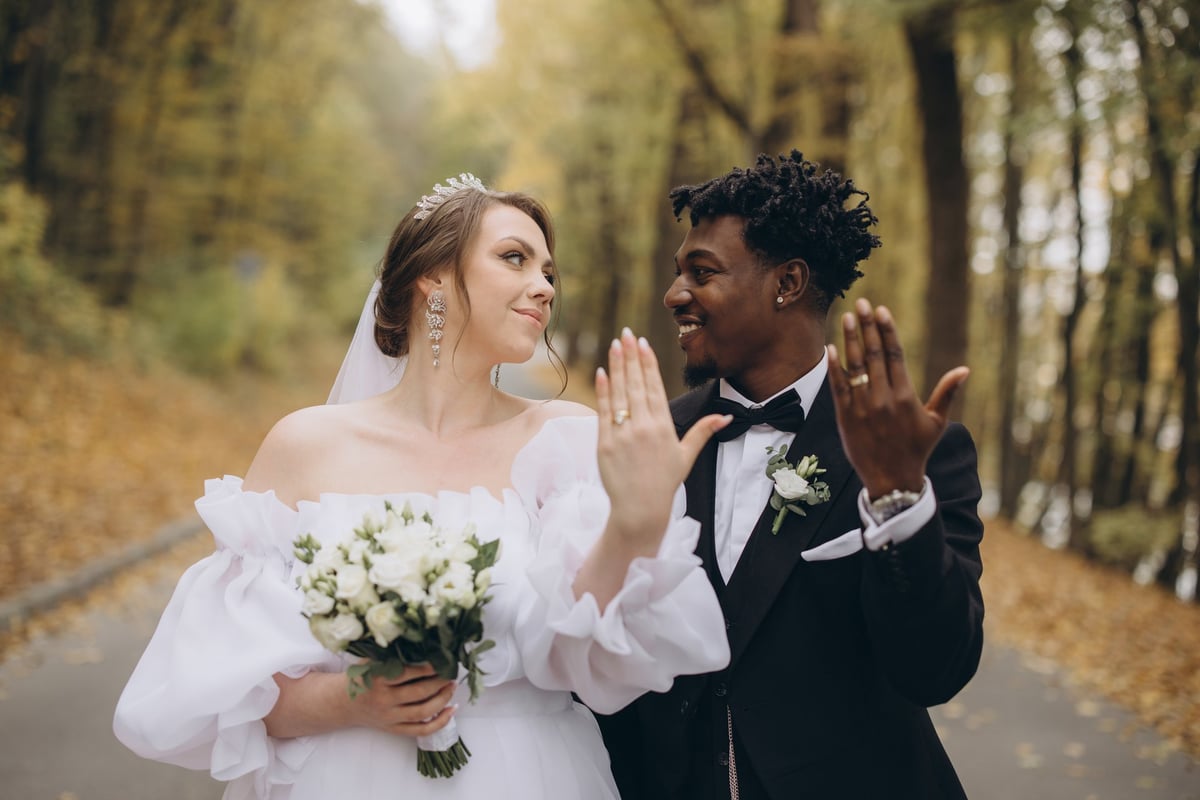 Newlyweds showing their wedding rings in a romantic autumn setting