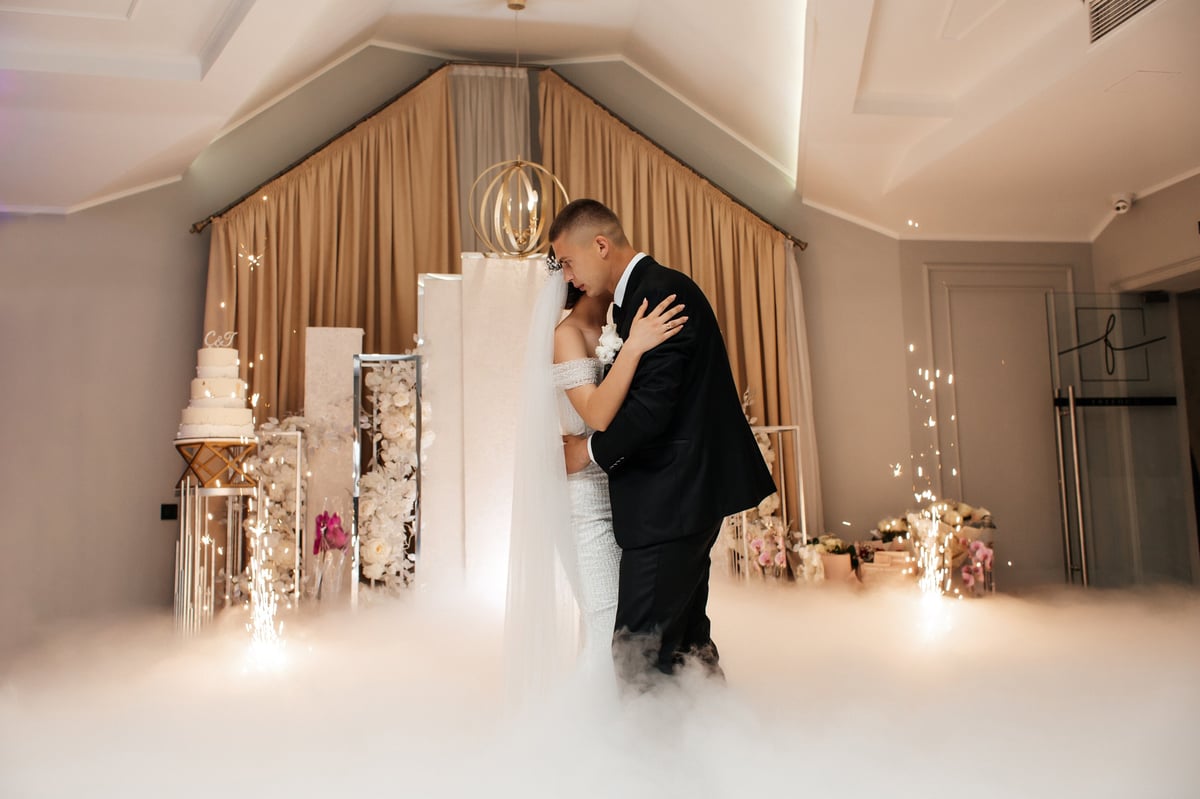Bride and groom dancing surrounded by soft white smoke on their wedding day